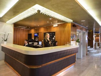 Moderní hotelová recepce se dvěma zaměstnanci a elegantním dřevěným designem.