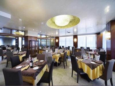 Moderní hotelová restaurace s prostřenými stoly a velkými okny.