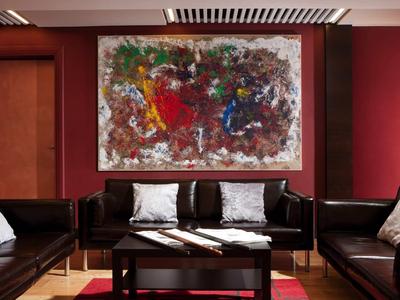 Lounge d'hotel moderna con divani in pelle marrone scuro, un tavolo nero e un grande dipinto astratto.