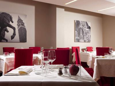 Ristorante elegante con tovaglie bianche, sedie rosse e foto in bianco e nero alle pareti.