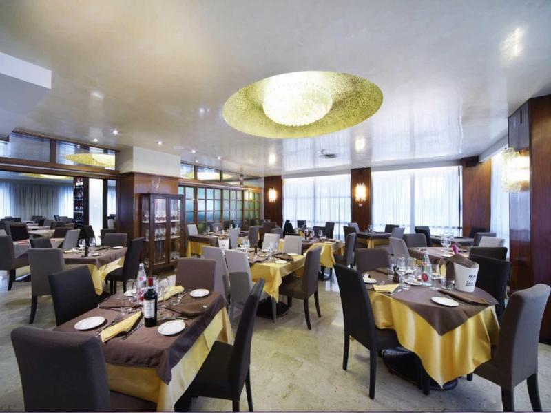 Moderní hotelová restaurace s prostřenými stoly a velkými okny.