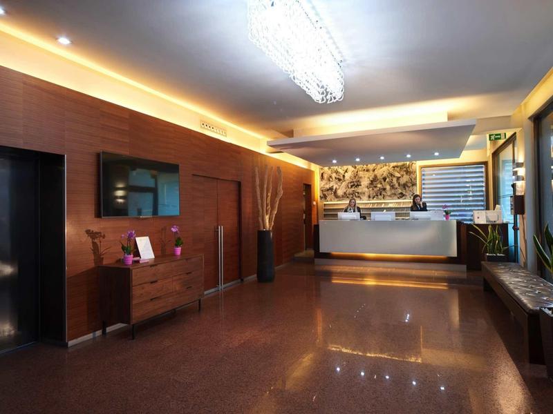 Moderní hotelová hala s recepcí, dřevěným obložením a lesklou podlahou.