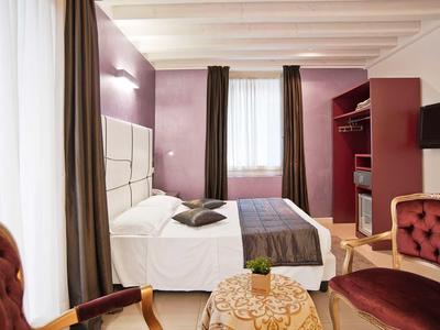 Elegancki pokój hotelowy z łóżkiem podwójnym, częścią wypoczynkową i fioletowymi ścianami.