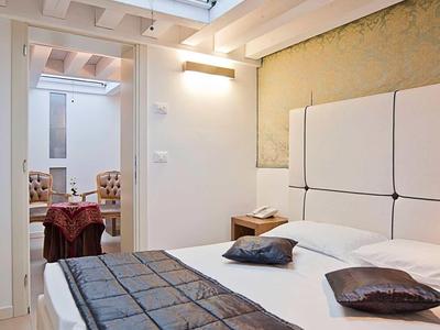 Nowoczesny pokój hotelowy z białym umeblowaniem, łóżkami i świetlikiem do naturalnego światła.