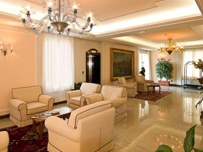 Elegantes Hotellobby mit beigen Sesseln, Kronleuchtern und Marmorboden