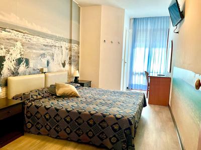 Cozy hotel room with double bed, wall decoration, and window with blue curtains.