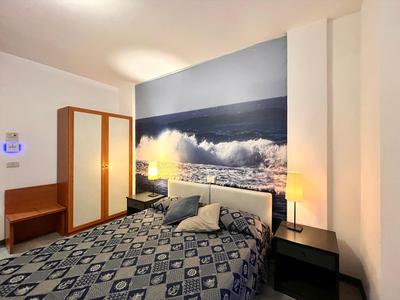 Modern hotel room with double bed and sea mural on the wall.