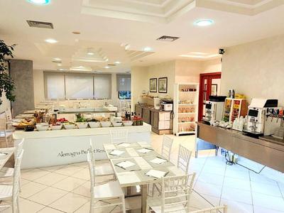 Bright breakfast room with white tables and chairs and a buffet area
