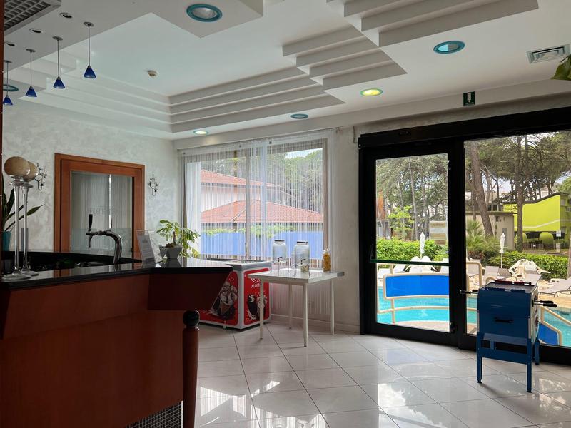 Modern hotel lobby with large window, seating area, and view of a pool.