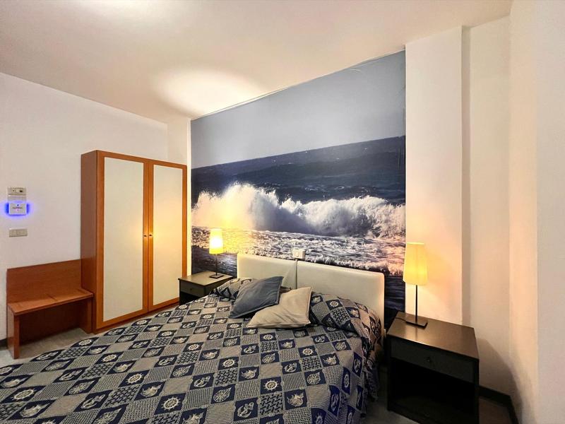 Modern hotel room with double bed and sea mural on the wall.