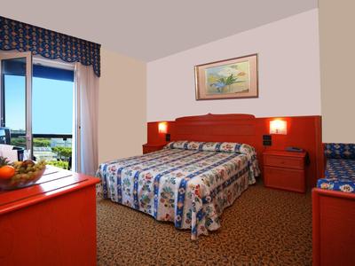 Gemütliches Hotelzimmer mit Doppelbett, buntem Teppich und Blick auf die Landschaft durch das Fenster.