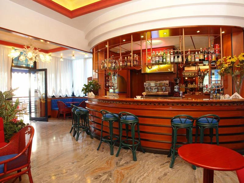 Hotelbar mit hölzernem Tresen, Barhockern und gemütlichen Sitzbereichen in warmem Ambiente