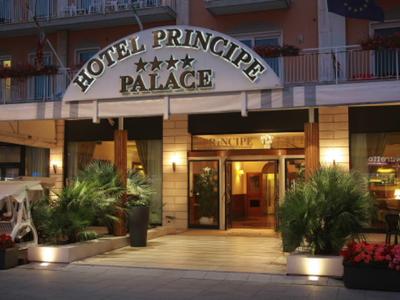 Der Eingang des Hotel Principe Palace mit beleuchtetem Schriftzug und Pflanzen rechts und links.