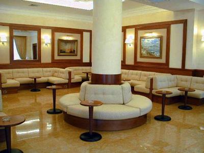 Hotel-Lounge mit runden Sofas um einen Säulenbereich und kleinen Tischen.