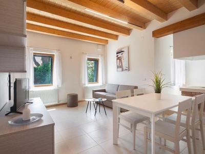 Helles Wohnzimmer mit Holzbalkendecke, Essbereich und Sofa neben Fenstern mit natürlichem Licht.