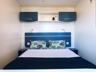 Modern eingerichtetes Hotelzimmer mit Doppelbett und Hängeschränken in Blau und Weiß.