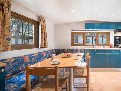 Gemütliche, helle Küchenecke mit blauem Sitzbereich und Holztisch, gedeckt mit Geschirr.