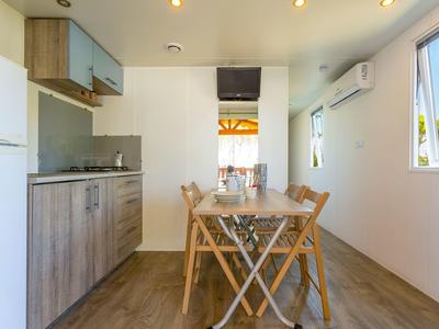 Kleine moderne Küche mit Holzmöbeln, Esstisch, Stühlen und Fenster mit Außenblick.