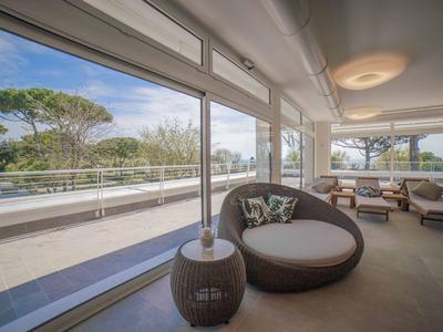 Moderner Hotel-Loungebereich mit großen Fenstern und Sicht auf Terrasse und Bäume.