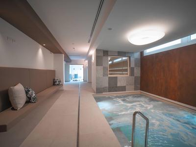 Moderner Innenpool mit beheiztem Wasser, gemütlichen Sitzgelegenheiten und warmem Licht.