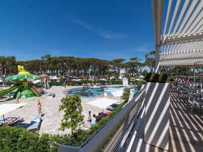 Blick auf einen Hotelpoolbereich mit Sonnenschirmen und Liegestühlen an sonnigem Tag