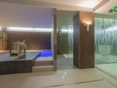 Moderner Wellnessbereich mit Whirlpool, beheiztem Pool und Glasduschen in neutralen Tönen.
