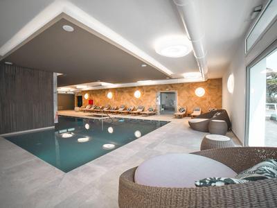 Moderner Innenpool mit loungigen Sitzgelegenheiten und großen Fenstern mit Außenblick.