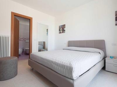 Modernes Schlafzimmer mit grauem Bett, weißer Bettdecke und offenem Badezimmer