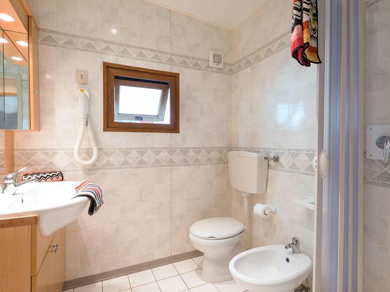 Helles Badezimmer mit Toilette, Bidet, Waschbecken, Spiegel und Duschkabine.