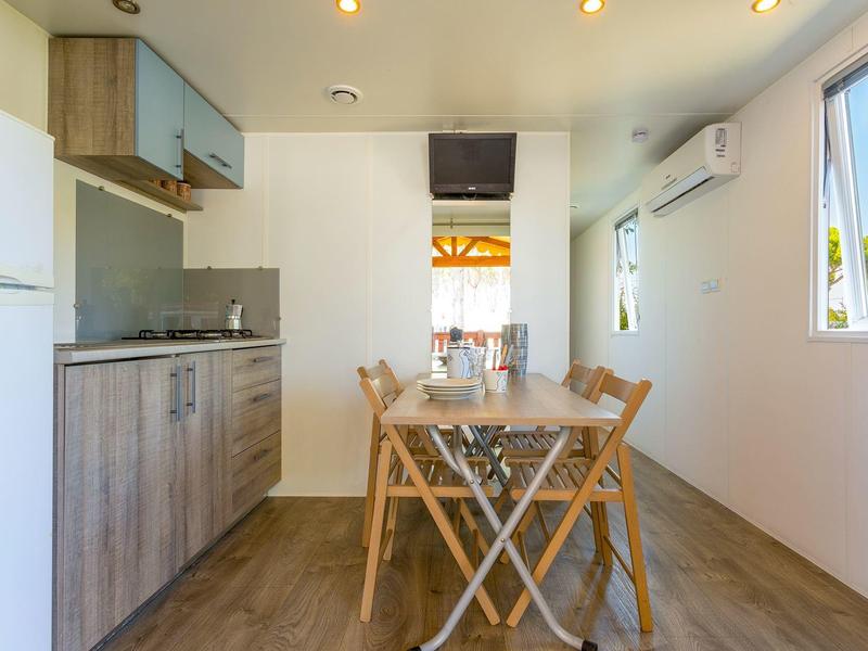 Kleine moderne Küche mit Holzmöbeln, Esstisch, Stühlen und Fenster mit Außenblick.