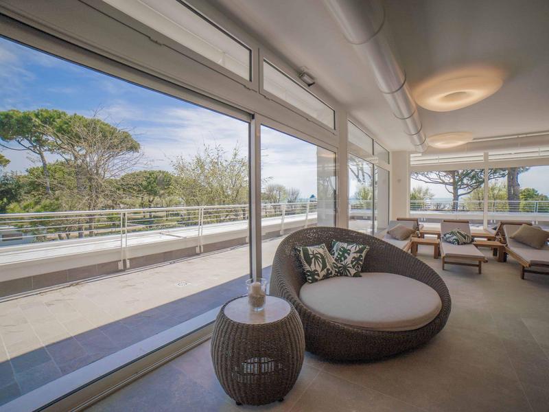 Moderner Hotel-Loungebereich mit großen Fenstern und Sicht auf Terrasse und Bäume.