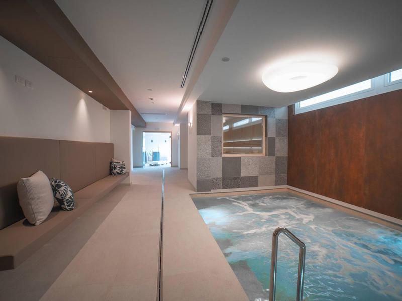 Moderner Innenpool mit beheiztem Wasser, gemütlichen Sitzgelegenheiten und warmem Licht.