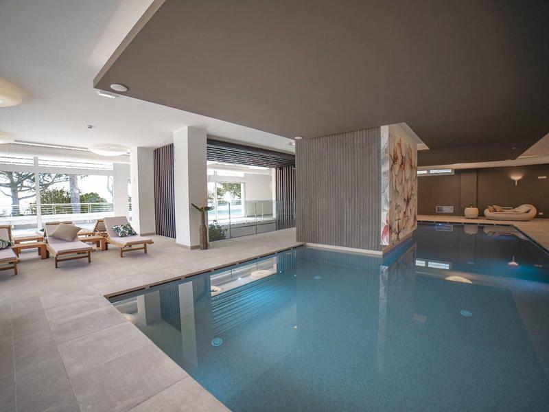 Modernes Hallenbad mit gemütlichem Sitzbereich und großem Fenster für Tageslicht.