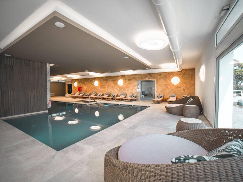 Moderner Innenpool mit loungigen Sitzgelegenheiten und großen Fenstern mit Außenblick.