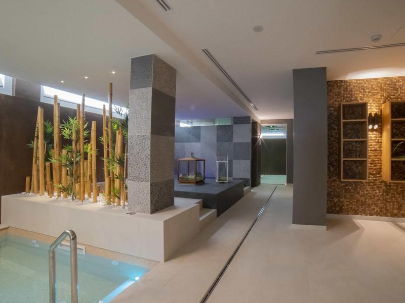 Modernes Spa mit Whirlpool, Bambuspflanzen und bequemen Sitzgelegenheiten in einem luxuriösen Innenbereich.