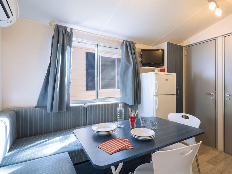 Modern eingerichteter Essbereich mit Tisch, Sitzecke und kleinem Kühlschrank in einer Unterkunft.