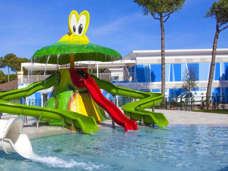 Wasserpark mit großer grün-gelber Wasserrutsche in Form eines Froschs und blauem Schwimmbecken.