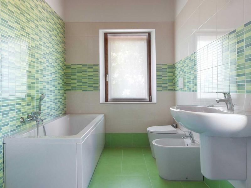 Modernes Badezimmer mit grünen Fliesen, Badewanne, Waschbecken, Bidet und Toilette.