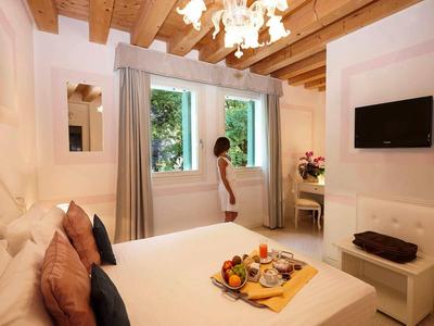 Helles Hotelzimmer mit Holzdecke, Doppelbett und Frau am Fenster