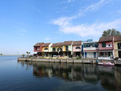 Reihenhaus neben ruhigem Wasser mit Himmelblick und leicht bewölktem Himmel.