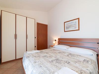 Ein schlicht eingerichtetes Hotelzimmer mit Doppelbett, großem Kleiderschrank und einem Bild an der weißen Wand.