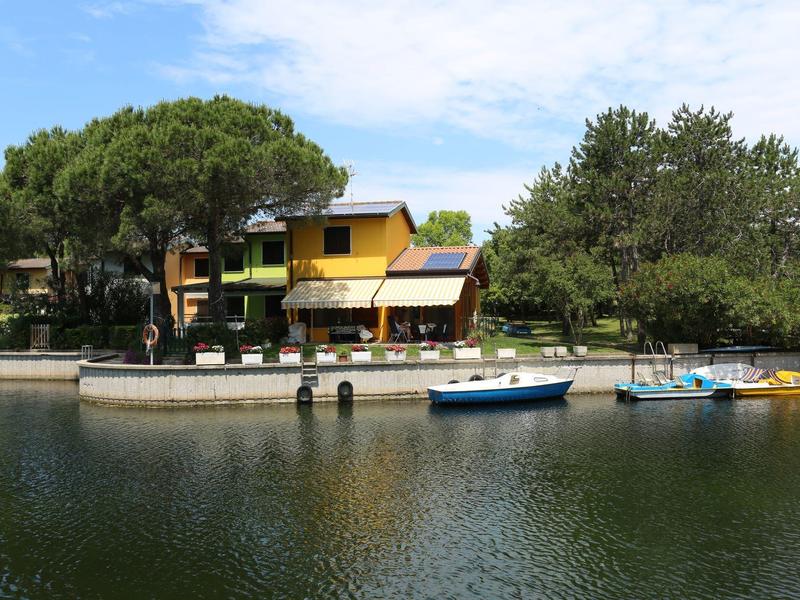 Gelbes Haus am Ufer mit Bootsanlegestelle und mehreren kleinen Booten im Wasser