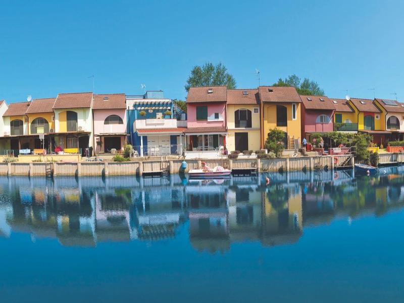 Farbenfrohe Häuser am Wasser mit klarer Spiegelung bei sonnigem Himmel