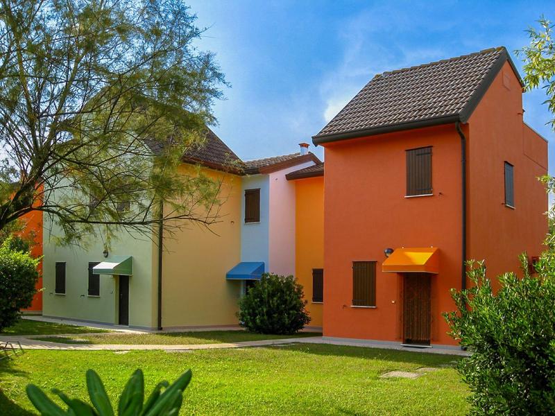 Bunte Ferienhäuser mit Grünfläche und blauem Himmel im Hintergrund.