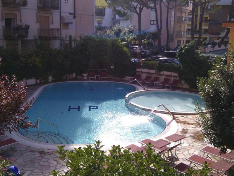 Ein kleiner, blau gefüllter Pool mit runden Formen, umgeben von Pflanzen und Wohngebäuden.