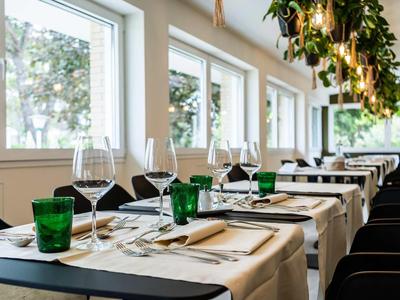 Restaurant élégant avec des tables dressées et de grandes fenêtres donnant sur l'extérieur.