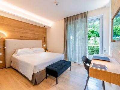 Modernes Schlafzimmer mit großem Bett, Holzvertäfelung, Schreibtisch und Zugang zum Garten.