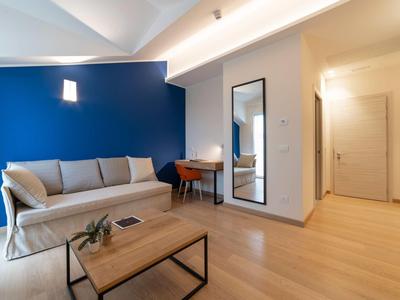 Moderner Wohnraum mit blau gestrichener Wand, hellgrauem Sofa, Holzfußboden und einfachem Holztisch.