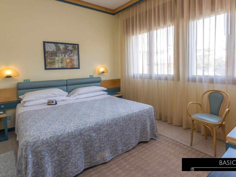 Cozy hotel room with double bed, large windows, and simple furnishings.