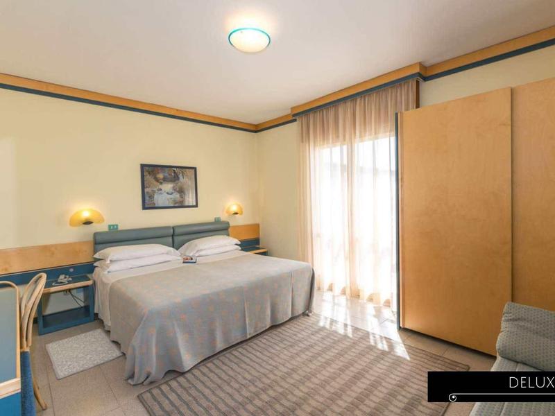 Brightly decorated double room with double bed, wardrobe, and TV in vacation hotel.